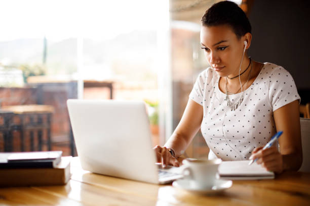 istock Attractive young woman working on laptop and taking notes at a cafe 913693234