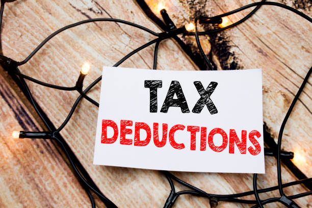 handwritten text caption showing tax deductions. business concept writing for finance incoming tax money deduction written on sticky note paper on the wooden background. - caption imagens e fotografias de stock