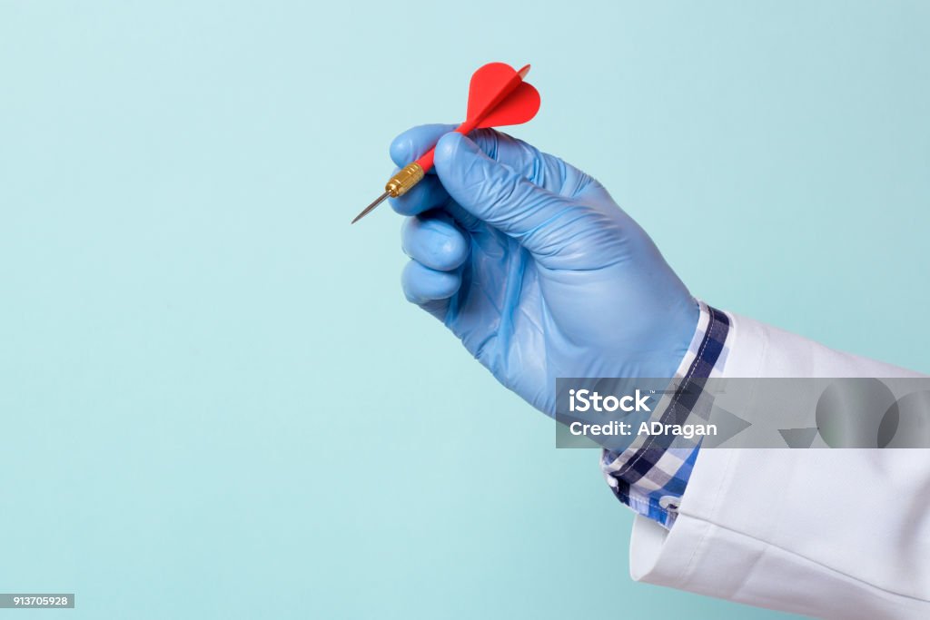 Doctor in a glove holds a red dart. Copy space for text Archery Stock Photo