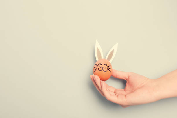 istock A hand holding little Easter bunny with paper ears 913708466