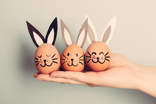 Three little Easter bunnies made from an egg held by woman's hand. Christianity traditions. Easter egg.