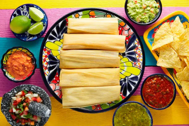 Tamale with corn leaf and sauces guacamole pico de gallo