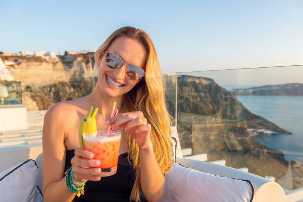 Horizontal color image of content woman having special banana drink on terrace and having fun.