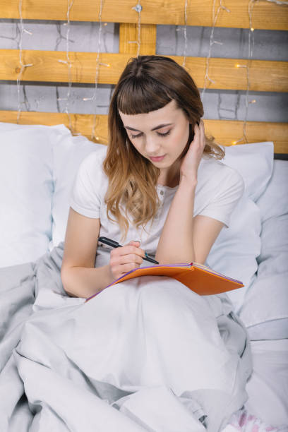 istock girl writing something to notebook in bed in morning 913717942