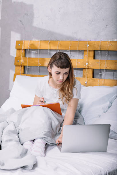 istock girl studying in bed in morning and using laptop 913718146