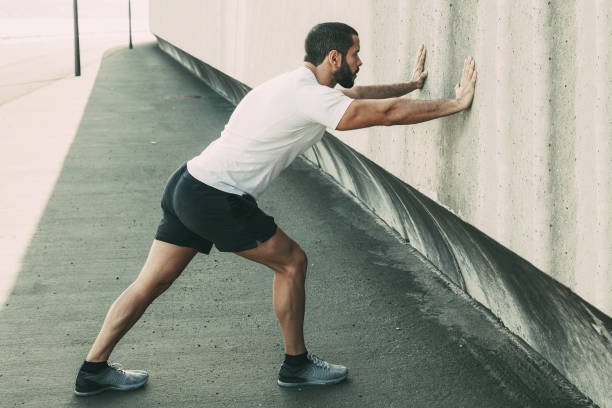 istock Strong Man Stretching Calf and Leaning on Wall 913720792