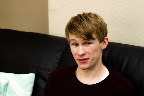 istock A young blonde man looking away at something in shock, while sat on a sofa 913726790