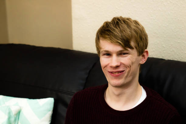 istock A young blonde man looking at the camera with a cheeky grin, while sat on a sofa 913726832