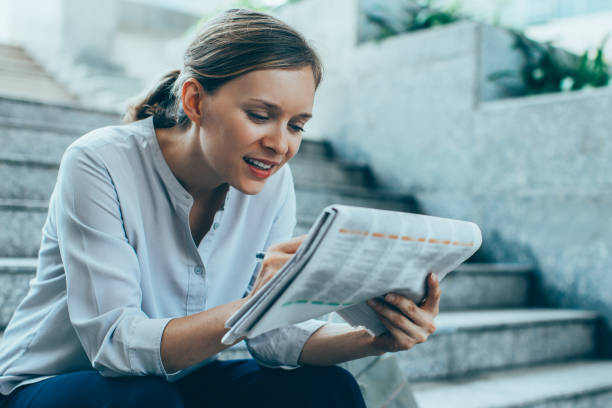 istock Content Lady Reading Newspaper on Stairs 913728964
