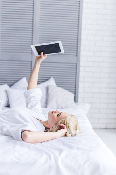 istock young woman lying on bed and using digital tablet with blank screen 913735566