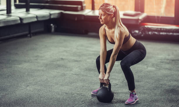 woman lifting kettlebell at gym. - kettle bell activity aerobics athlete imagens e fotografias de stock