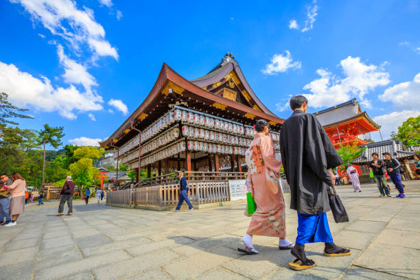 Kyoto, Japan - April 24, 2017:japanese couple in traditional clothes walking near ancient wooden pavilion of main hall decorated with paper lanterns.Yasaka Shrine is one of most famous shrine in Kyoto