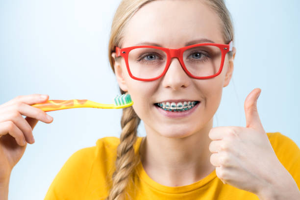 istock Woman smiling cleaning teeth with braces 913757686