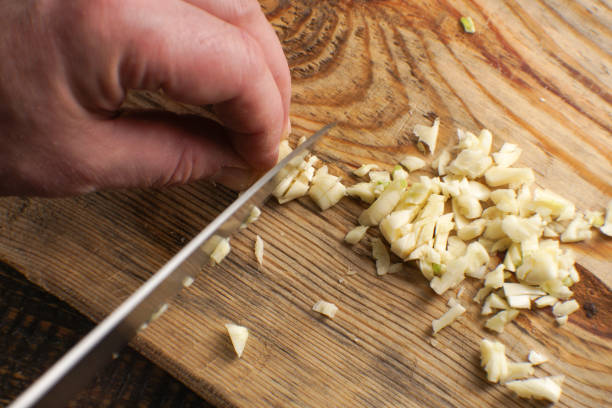 istock Man cuts garlic into small pieces on a wooden board 913760326