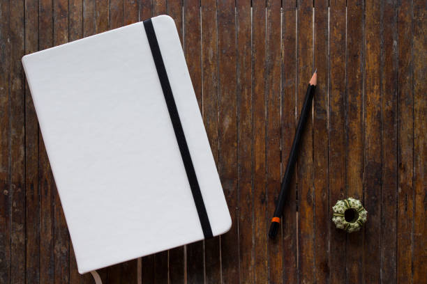 istock White cover notebook with black pencil on rustic wooden table flat lay photo. 913764930