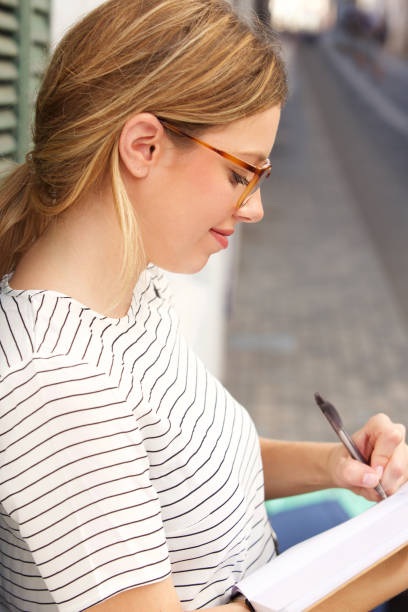 istock young woman writing with pen in book 913777722