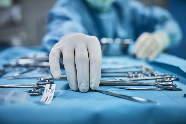 chirurgo che raccoglie lo strumento chirurgico dal vassoio - medical supplies scalpel surgery equipment foto e immagini stock