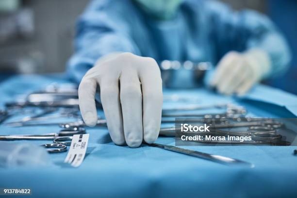 Surgeon Picking Up Surgical Tool From Tray Stock Photo - Download Image Now - Surgery, Medical Equipment, Surgical Equipment