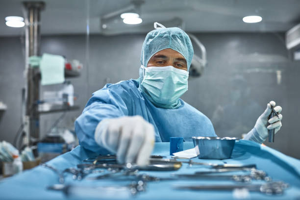 chirurgo che raccoglie utensili chirurgici dal vassoio - picking up safety working men foto e immagini stock