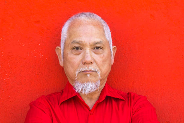 istock Asian man standing in front of red colored wall 913785930