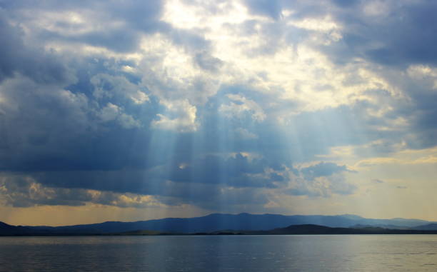 istock Bright sun's rays passing through the storm clouds over the lake 913800874