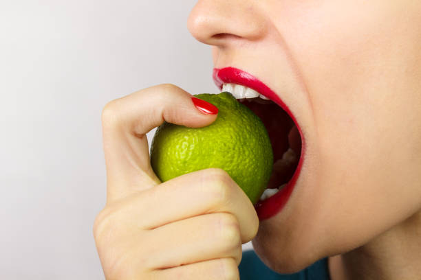 młoda kobieta gryźć jeść świeżą wapno izolowane na białym tle - lemon sour taste biting eating zdjęcia i obrazy z banku zdjęć