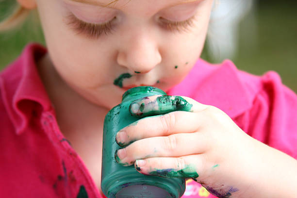 The child is showing her colorful hands and making a shape with her fingers outside.