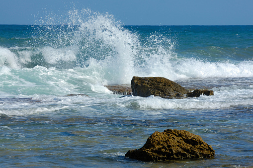 White-capped waves approaching a blue pebble beach background poster with copy space. Computer-generated image photography.