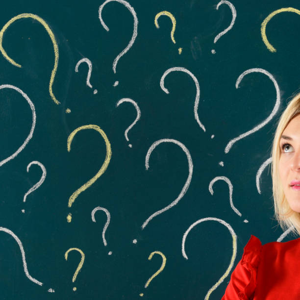 istock Pensive Woman in front of Blackboard with Question Marks 913807872