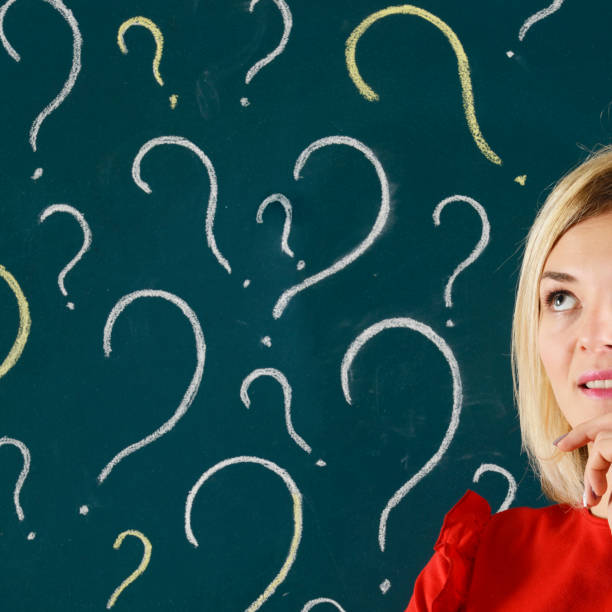 istock Pensive Woman in front of Blackboard with Question Marks 913807884