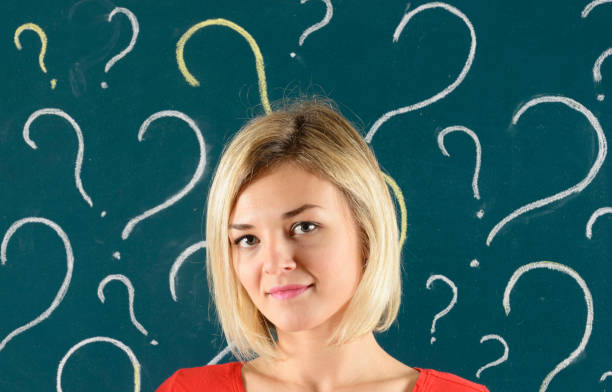 istock Pensive Woman in front of Blackboard with Question Marks 913807898