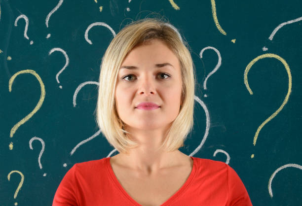 istock Pensive Woman in front of Blackboard with Question Marks 913807914