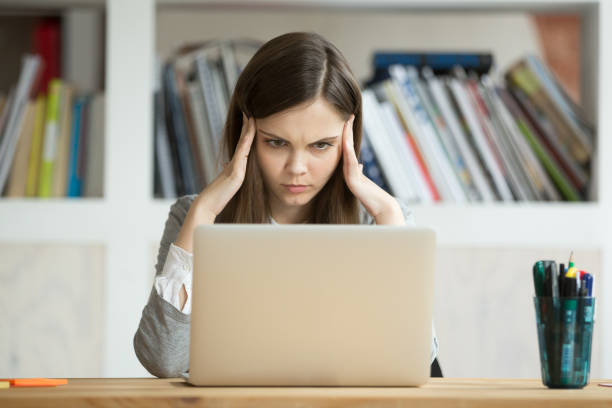 Focused concerned girl student learning difficult exam with laptop online