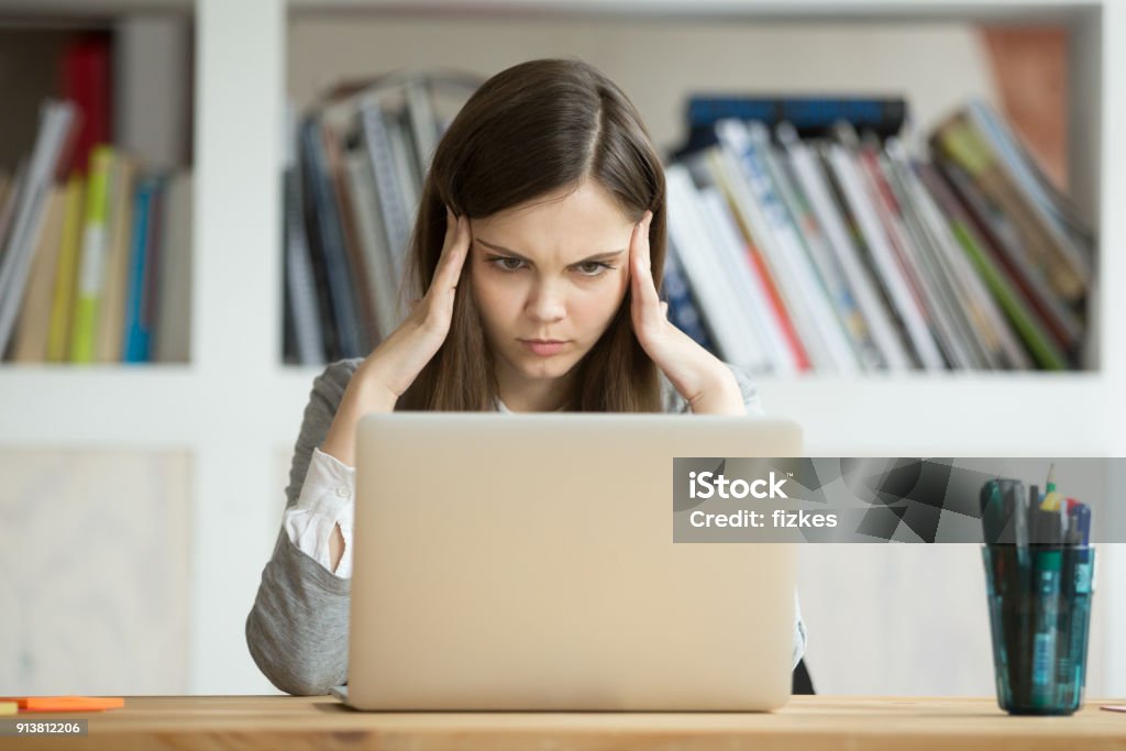 Focused concerned girl student learning difficult exam with laptop online Focused concerned student learning difficult homework assignment with laptop online, concentrated girl preparing for digital exam on pc, serious young woman thinking hard on task with computer Concentration Stock Photo