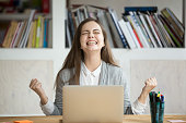 Excited female student feeling euphoric celebrating online win success achievement