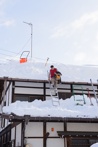 Takayama, Japan - January 17,2017 : Japanese man removing snow from the roof.