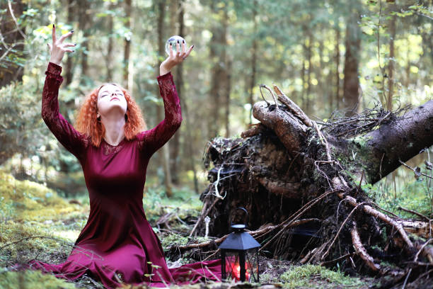 istock The red-haired witch holds a ritual with a crystal ball 913823024
