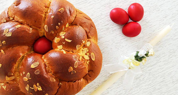 Traditional Easter bread ,tsoureki with a red egg in the middle , tree red eggs and an Easter candle beside