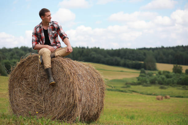 istock Young man in boots in a village field sunset 913858518