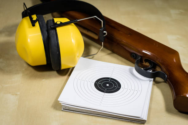 istock Shooting accessories on a wooden table in a shooting range. Shield and projectiles for pneumatic weapons before shooting. Black background. 913859252