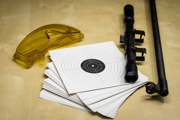 istock Shooting accessories on a wooden table in a shooting range. Shield and projectiles for pneumatic weapons before shooting. Black background. 913859278