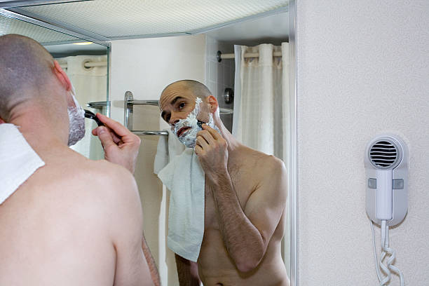 Man Shaving in Hotel Bathroom  accustom stock pictures, royalty-free photos & images