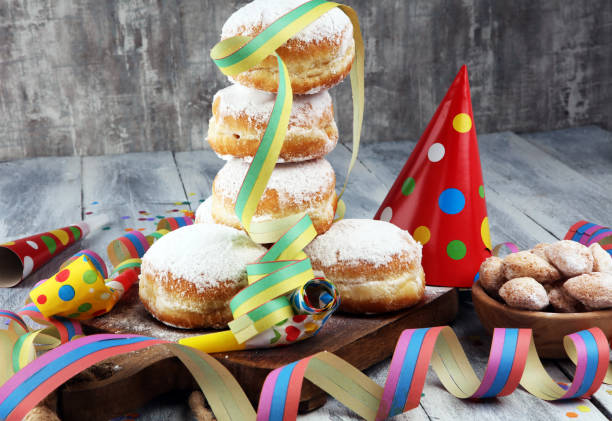 istock German donuts with jam and icing sugar. Carnival powdered sugar raised donuts with paper streamers. 913865260