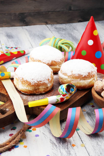 istock German donuts with jam and icing sugar. Carnival powdered sugar raised donuts with paper streamers. 913865328
