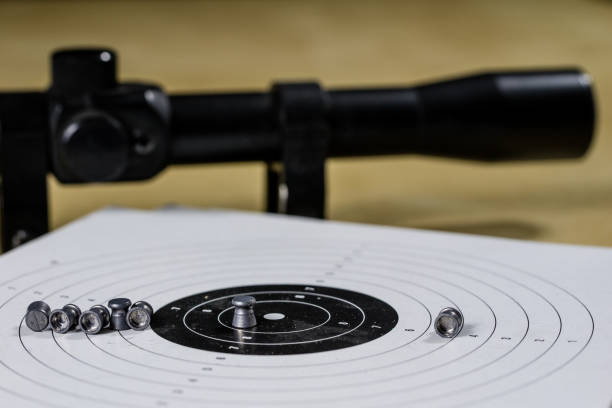 istock Shooting accessories on a wooden table in a shooting range. Shield and projectiles for pneumatic weapons before shooting. Black background. 913865662