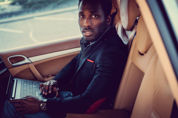 istock African man in a suit using laptop in a car. 913866366