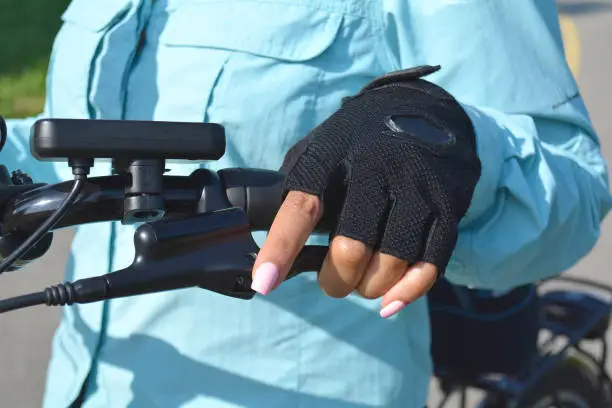 Photo of Woman hand with bright pink nails on the electric bicycle handle with computer. Healthy life style concept. Hand holding e bike handlebar with ebike scooter display.