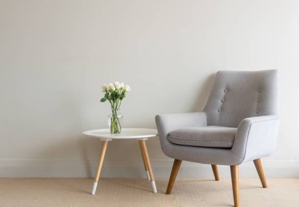 istock Retro armchair with roses in vase on table against wall 913882898