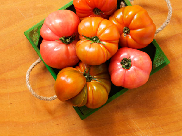 Pink tomatoes in wooden case Pink tomatoes in wooden case basket healthy eating vegetarian food studio shot stock pictures, royalty-free photos & images