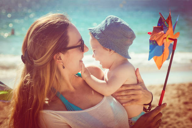 istock Mother and son playing with pinwheel on the beach 913883610